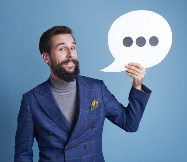 Cheerful businessman with speech bubble posing at studio shot