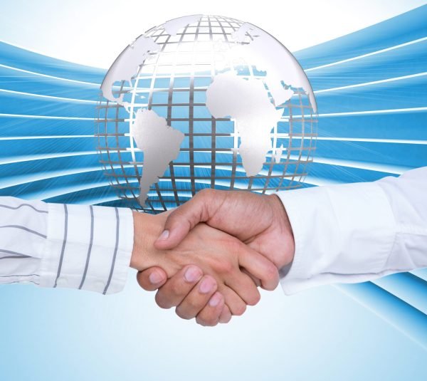 Digital composition of business executives shaking hands against globe in background